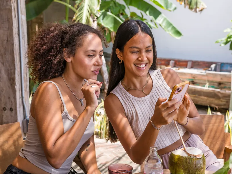 Two friends looking at a phone while booking ferry tickets